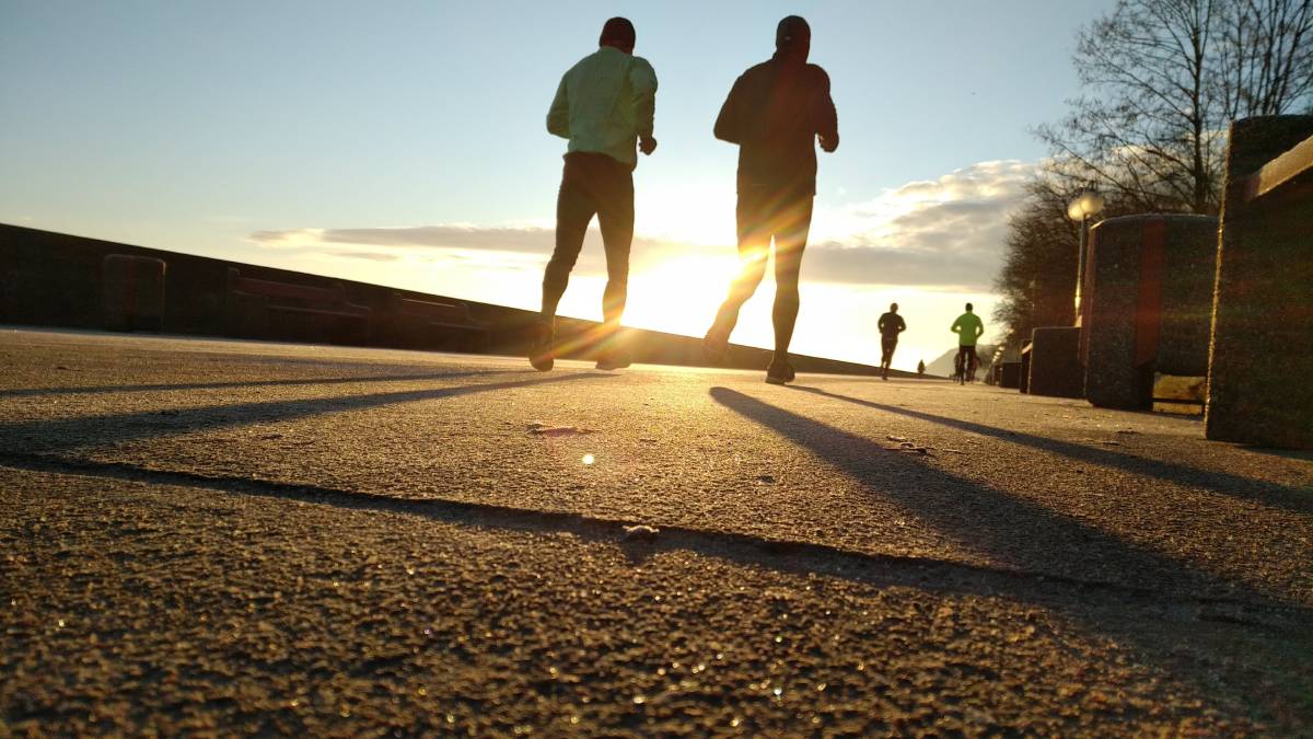 People running on a concrete path at sunrise or sunset